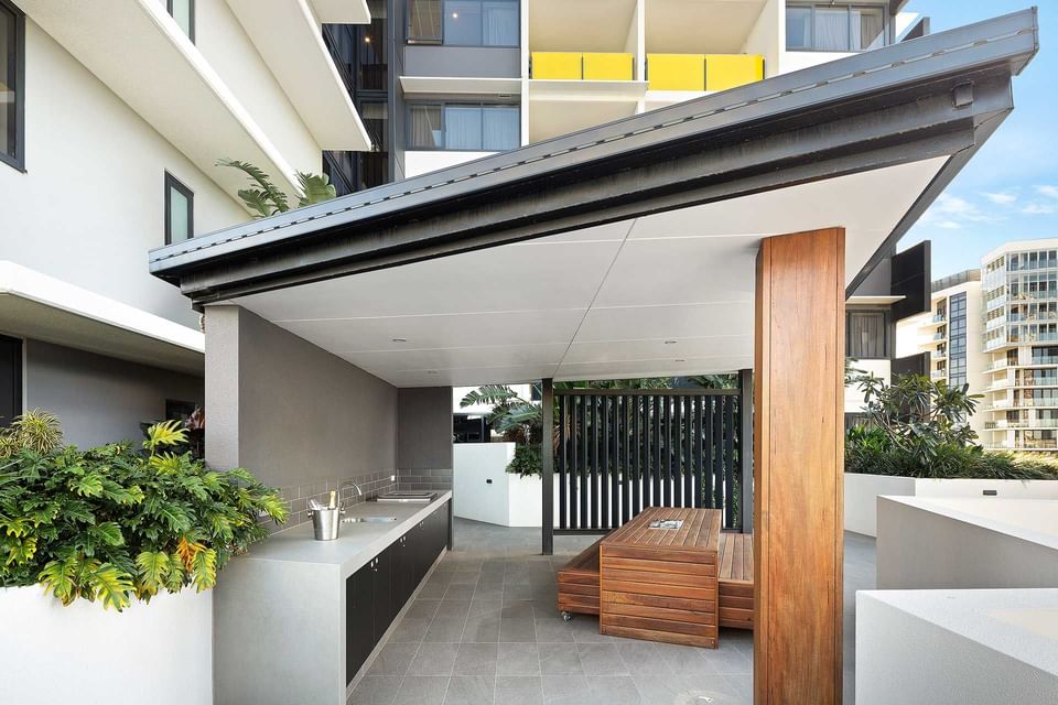 Outdoor BBQ area with arranged wooden seats and vanity with tiled floors at Alcyone Hotel Residences