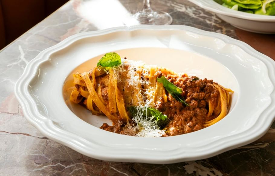Plate of spaghetti Bolognese topped with grated cheese, served at Bar Remi in Granduca Houston