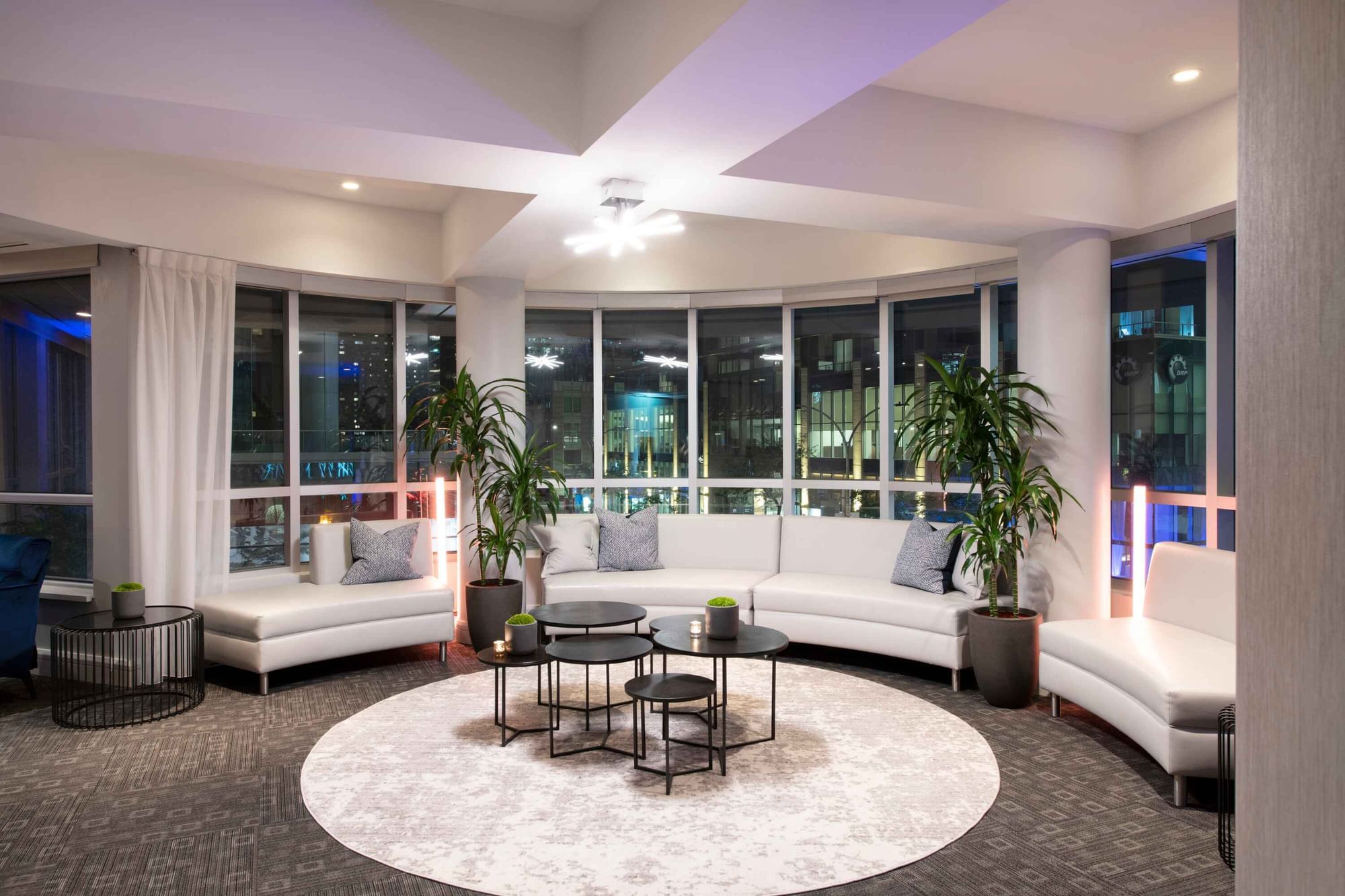 Lounge with white sofas and large windows overlooking the city skyline in the Ballroom at Warwick Hotels and Resorts