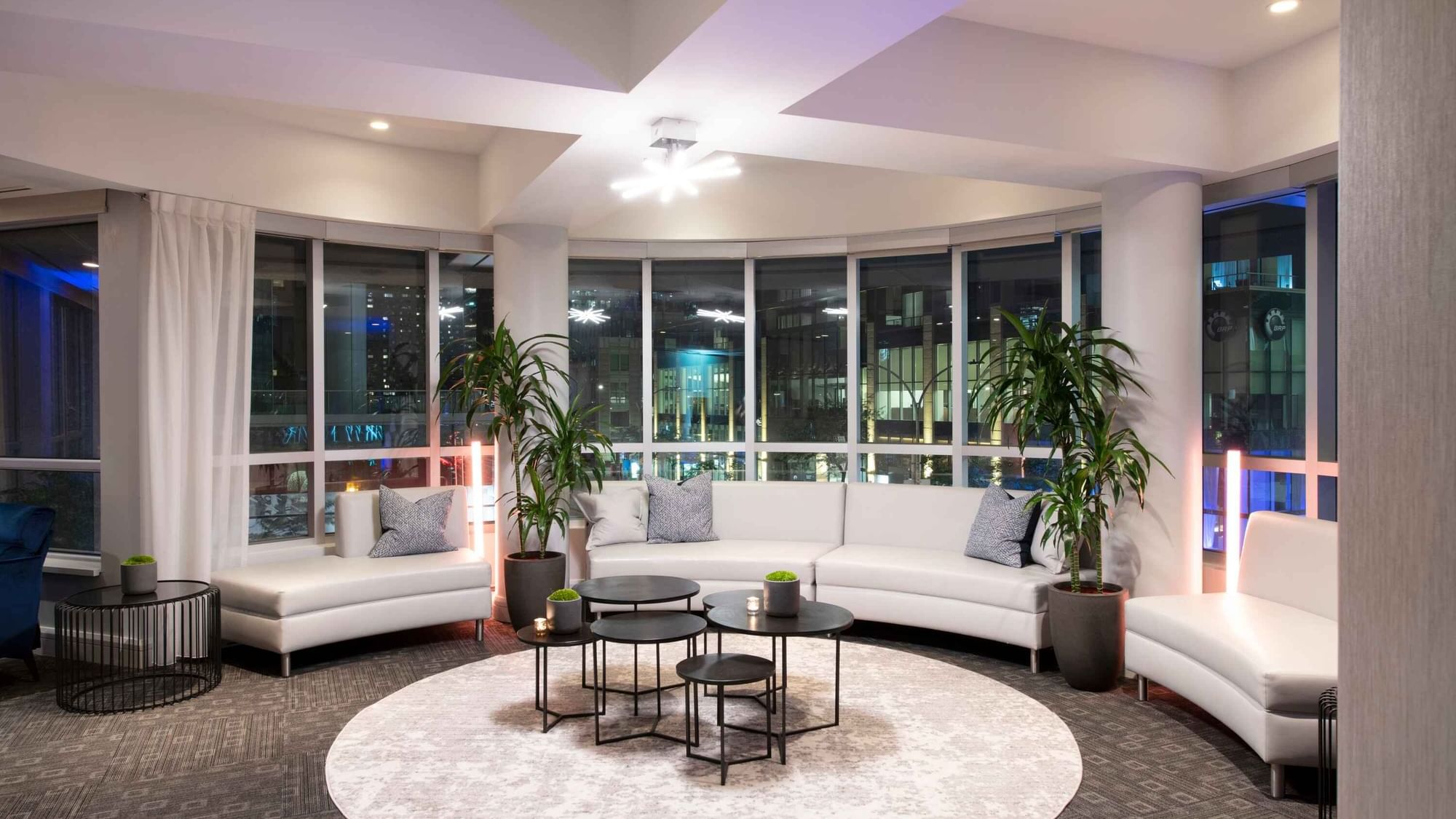 Lounge with white sofas and large windows overlooking the city skyline in the Ballroom at Warwick Hotels and Resorts