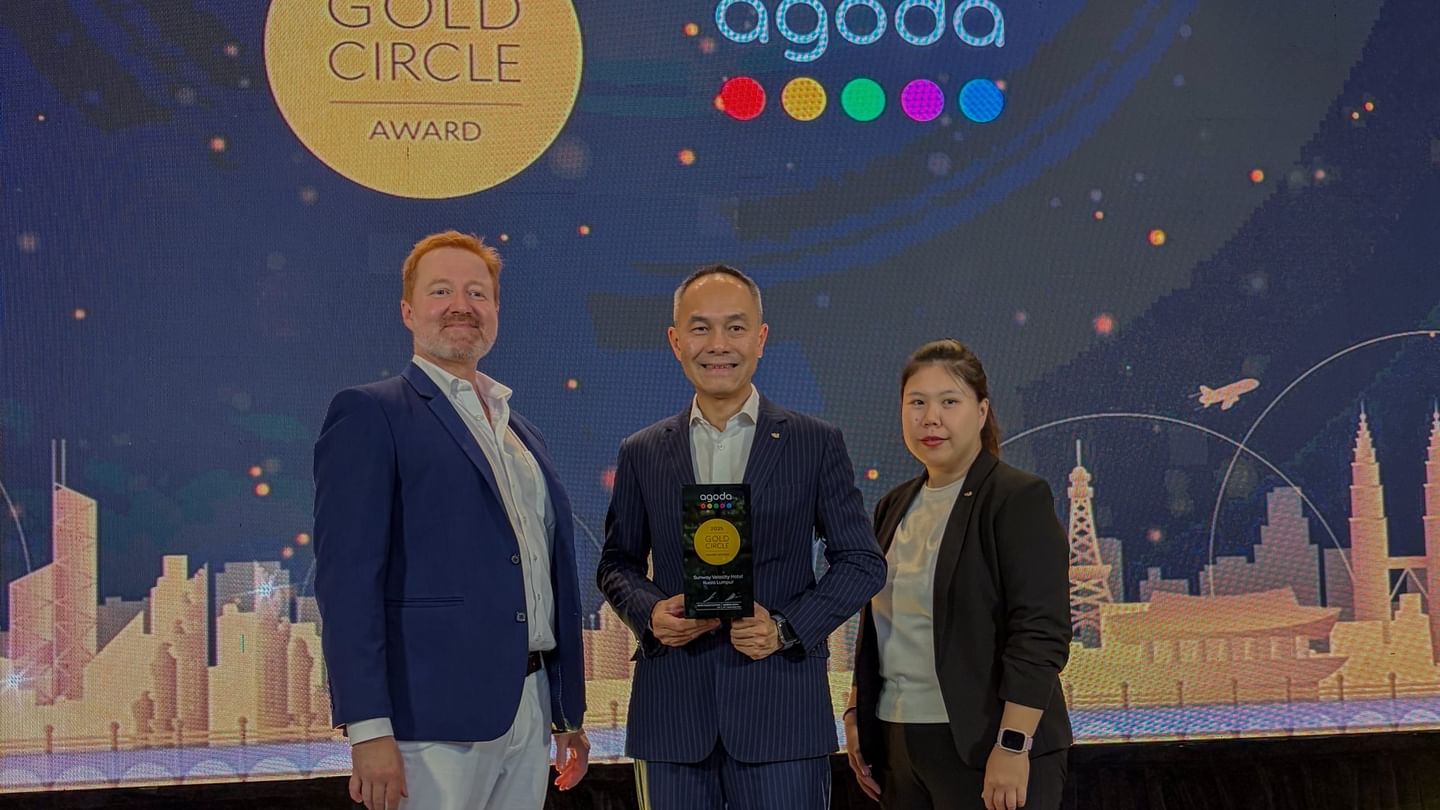 Three people holding an award in front of a Gold Circle Award sign.