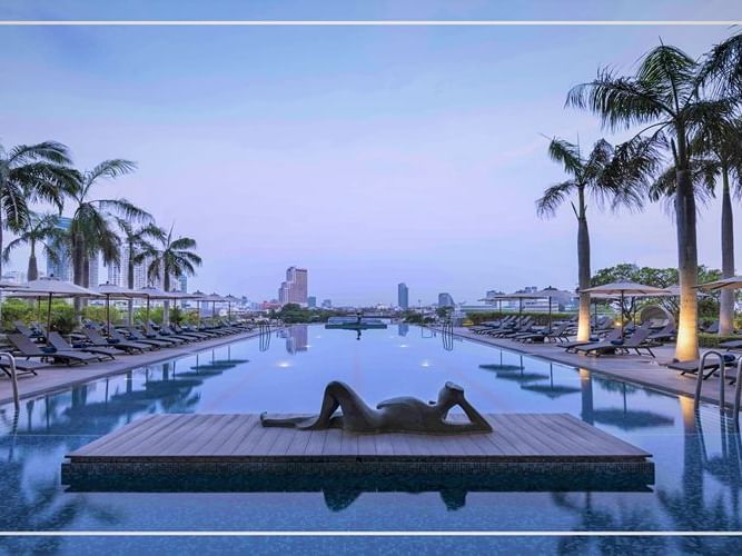 Floating deck with a sculpture in the pool at Chatrium Hotel