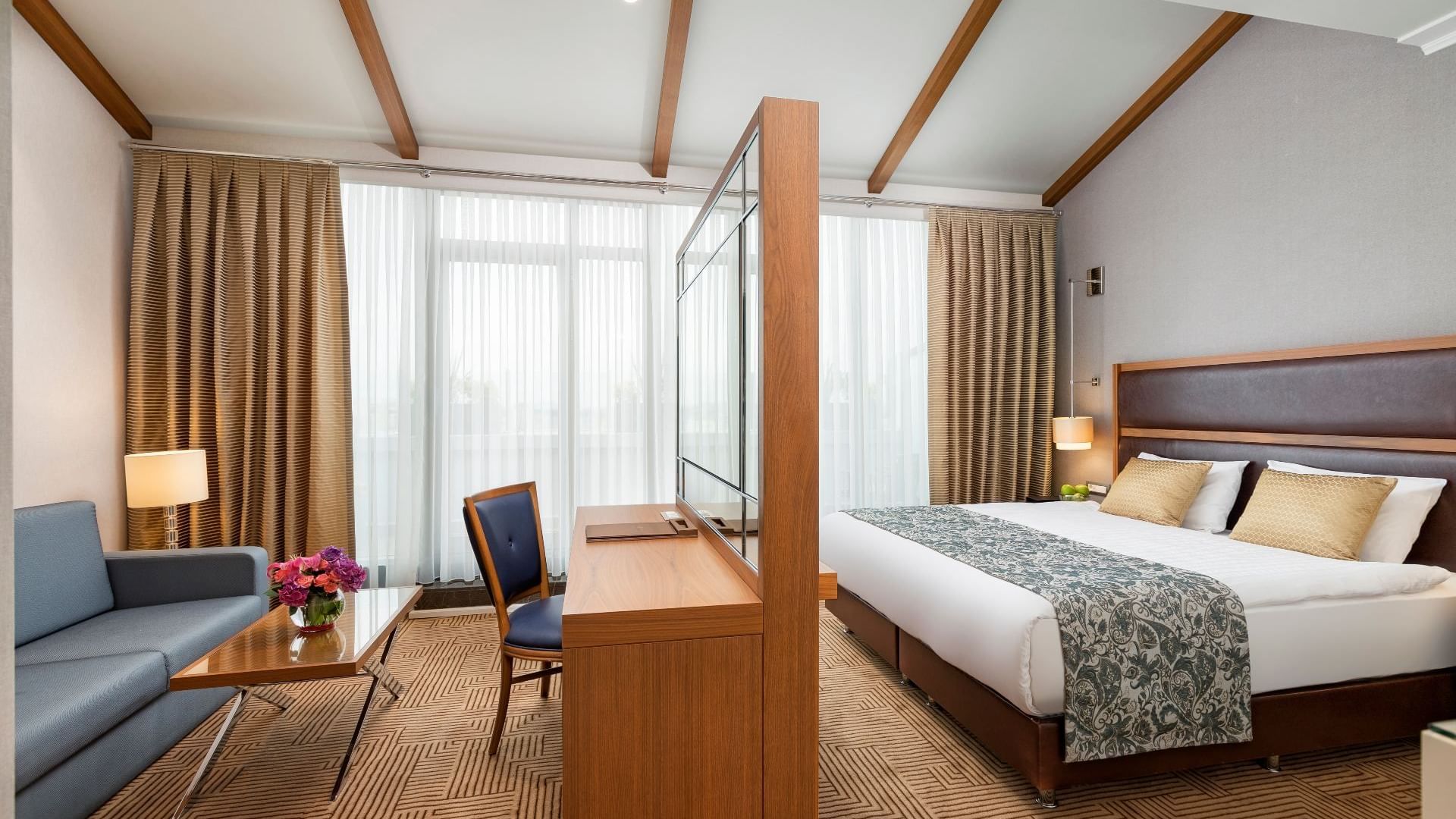 Titanic City Taksim’in Executive odasında, deri koltuklu TV oturma alanı ve konforlu yatak ile şıklık ve rahatlık bir arada.