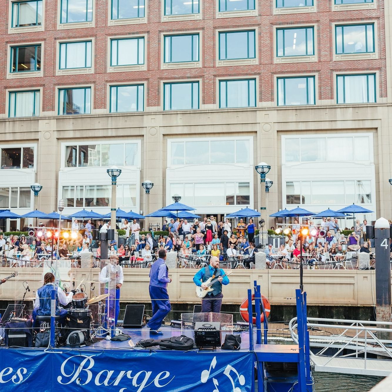 Band playing in front of crowd on floating harbor barge.