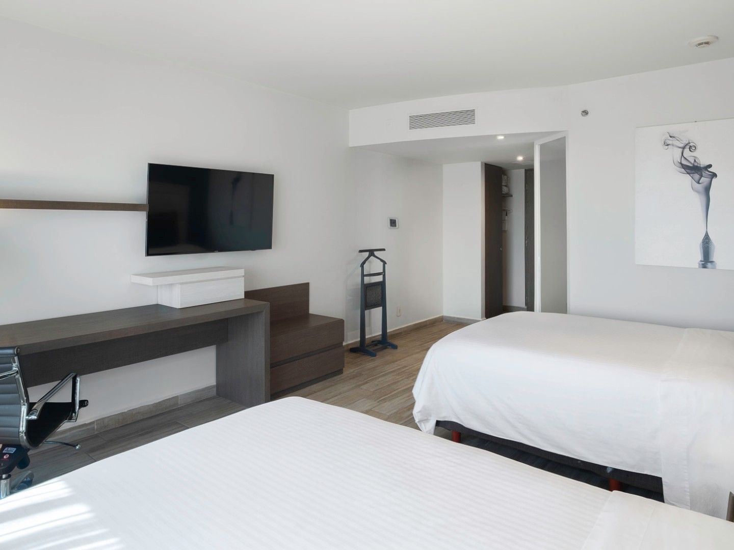 Habitación de lujo con dos camas dobles, televisor y escritorio en el Real Inn Perinorte de Tlalnepantla.