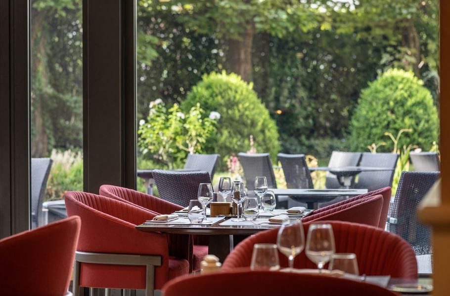 Le Lounge Restaurant interior with red chairs and modern tables set with glassware at Warwick Reine Astrid - Lyon