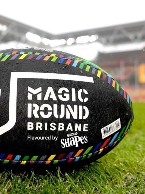 Magic Round rugby ball on grass in front of a stadium.