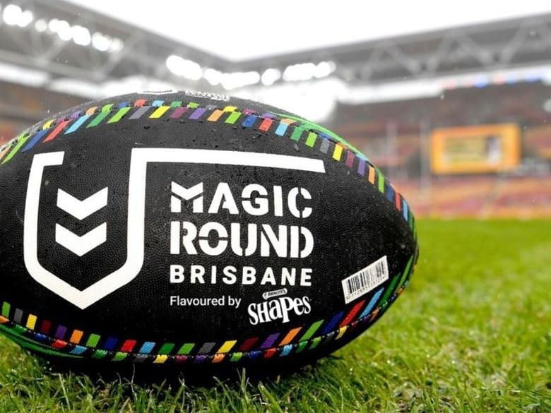 Magic Round rugby ball on grass in front of a stadium.