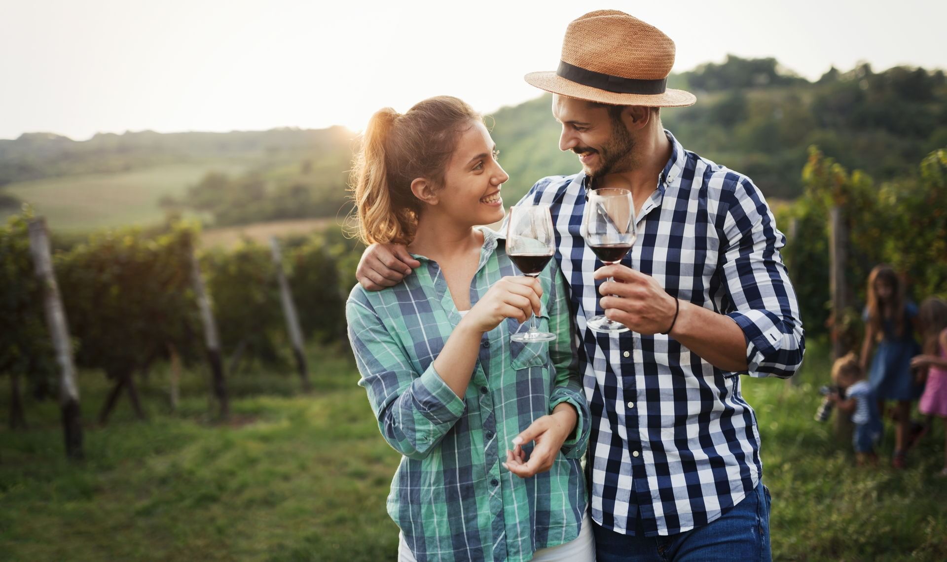 Couple smiling and drinking red wine at vineyard