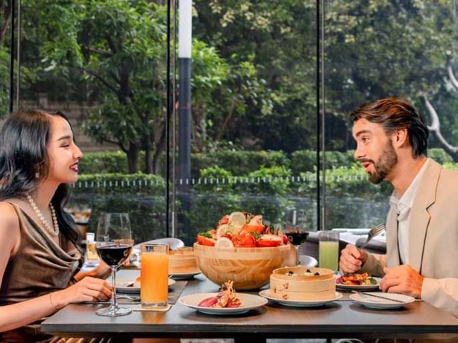 A man and woman enjoy a meal together at a restaurant, sharing a moment of conversation and dining experience.