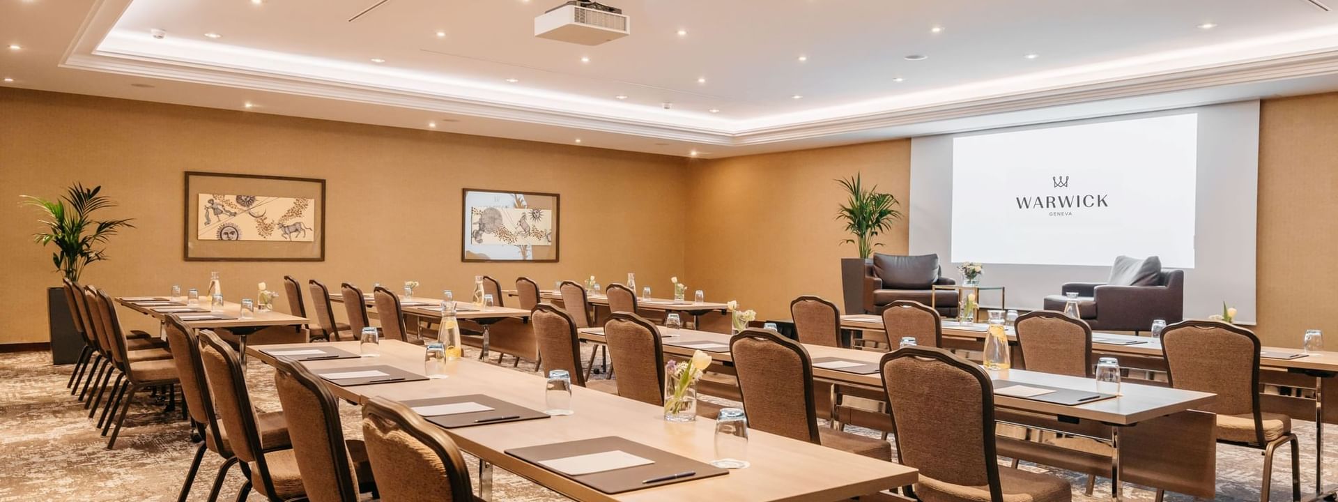 Long wooden desks by rows of chairs under a ceiling projector in Mont-Blanc + Jura at Warwick Geneva