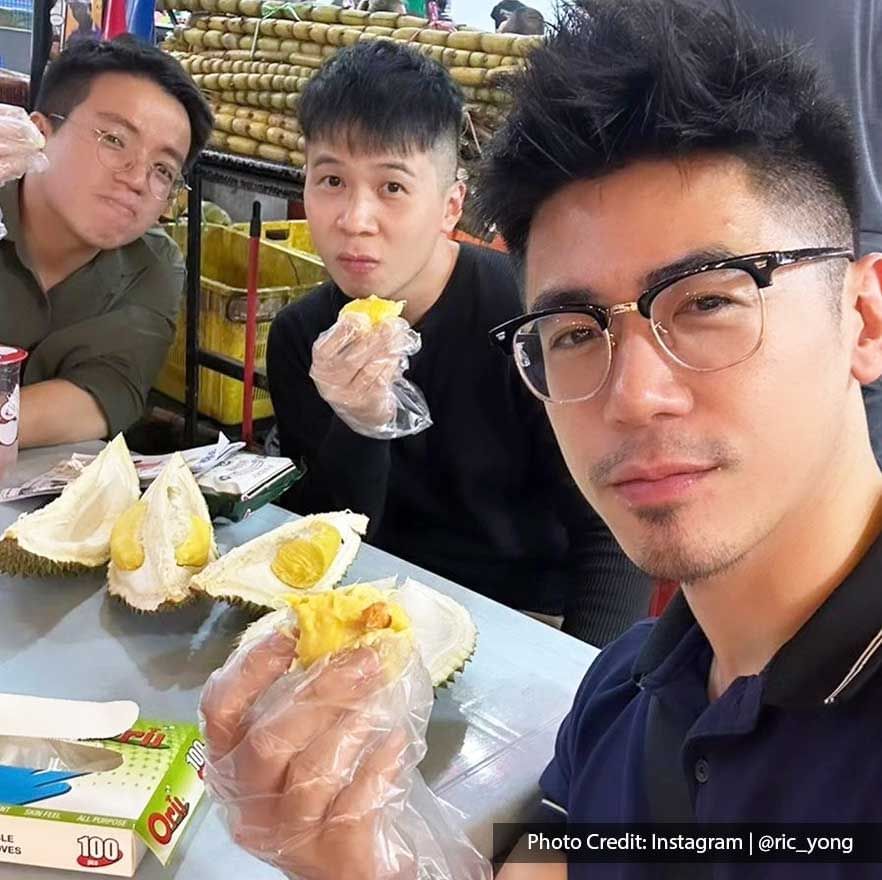 Three men enjoying a durian fruit from a street food stall, KL Food Guide near Imperial Lexis Kuala Lumpur