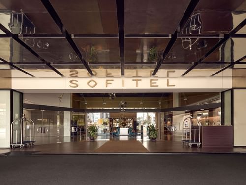 Entrance of Sofitel Brisbane Central Hotel with reflective ceiling and luggage trolley on the side