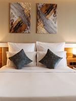 Plush bed with grey cushions by wooden nightstands in Superior King / Queen Room at Cantonal Hotel by Warwick Riyadh