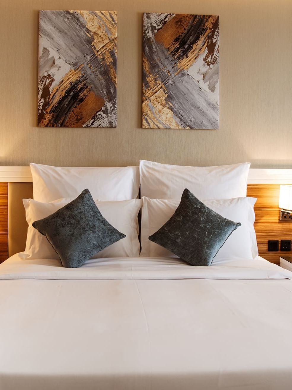 Double bed with white linens by wooden headboards in Standard King Room at Cantonal Hotel by Warwick Riyadh