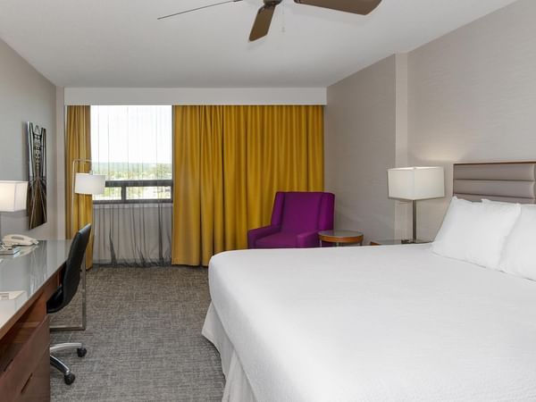 Coast King room with king bed, purple accent chair, work desk, and yellow curtains at Coast Prince George Hotel.