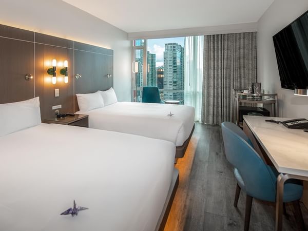 Two queen beds with white linens and a desk in a modern room.