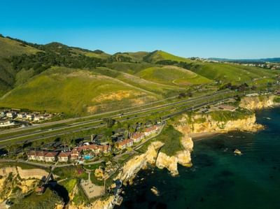Aerial view of hotel and Pismo Preserve with green hills