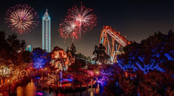 Fireworks over a roller coaster and tower by dark trees and a lake at Knott's Berry Farm near Anaheim Portofino Inn & Suites