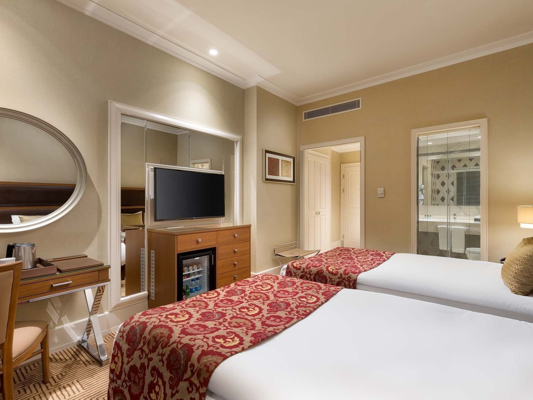 Two comfy beds, TV and mirror table in a room at Titanic City Taksim