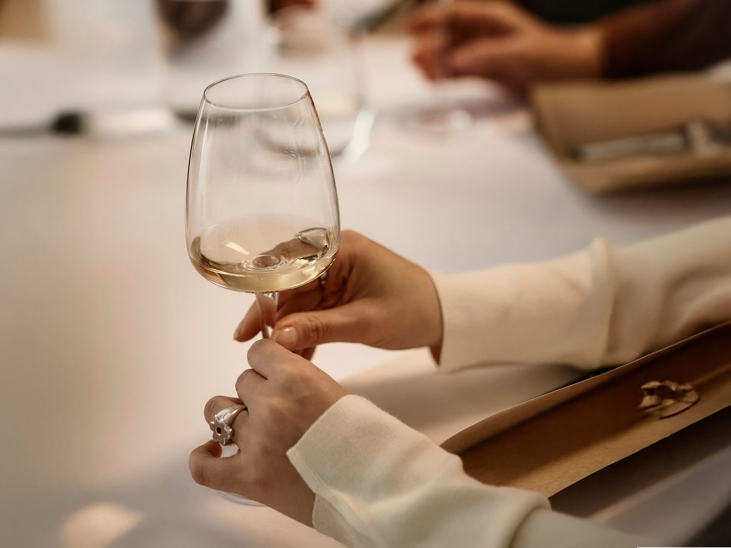 Guest holding a glass of white wine at Quinta Real Aguascalientes during a formal dinner event at the hotel