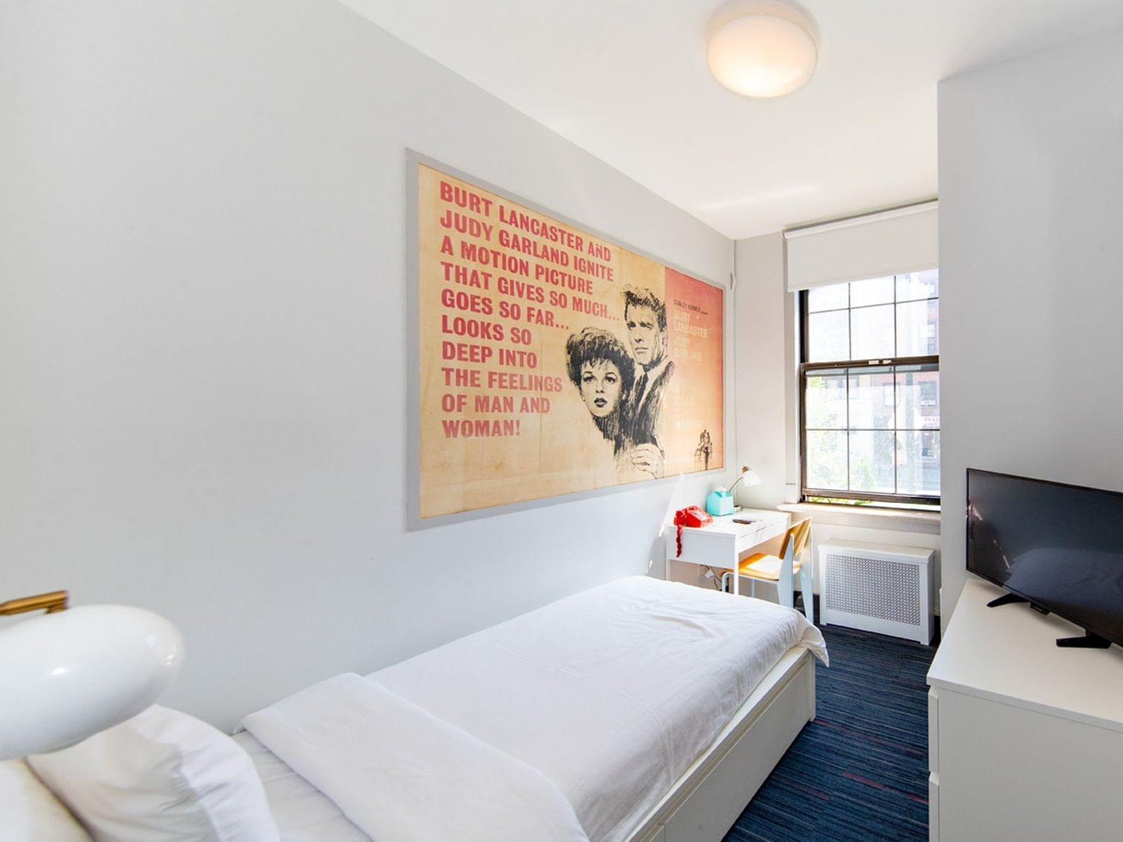 Single Room with bed, desk, TV, and movie poster at Chelsea Pines Inn, New York.