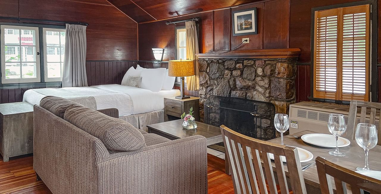 Cabin with bed, kitchen, couch, table, and a fire place