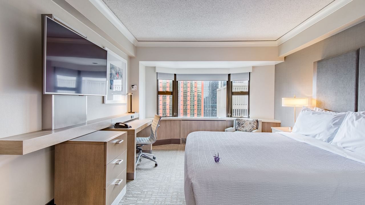 Hotel guestroom with king bed, TV, and desk