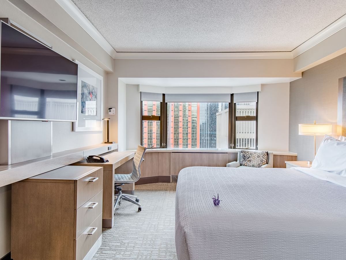 Hotel guestroom with king bed, TV, and desk