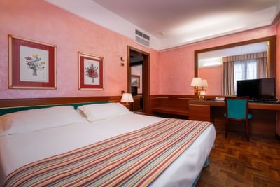 Comfy bed with large mirror & work area in Executive Suite at Hotel Crivi's in Milan
