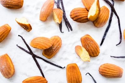 Golden madeleines sprinkled with sugar, scattered on sugar with vanilla beans in The Pastry Boutique at Park Hyatt Saigon