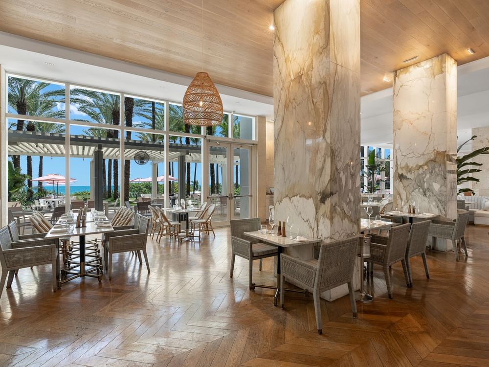 Le restaurant aux colonnes et aux chaises tressées du Grand Beach Hotel Surfside, parmi les restaurants exceptionnels de Miami Beach
