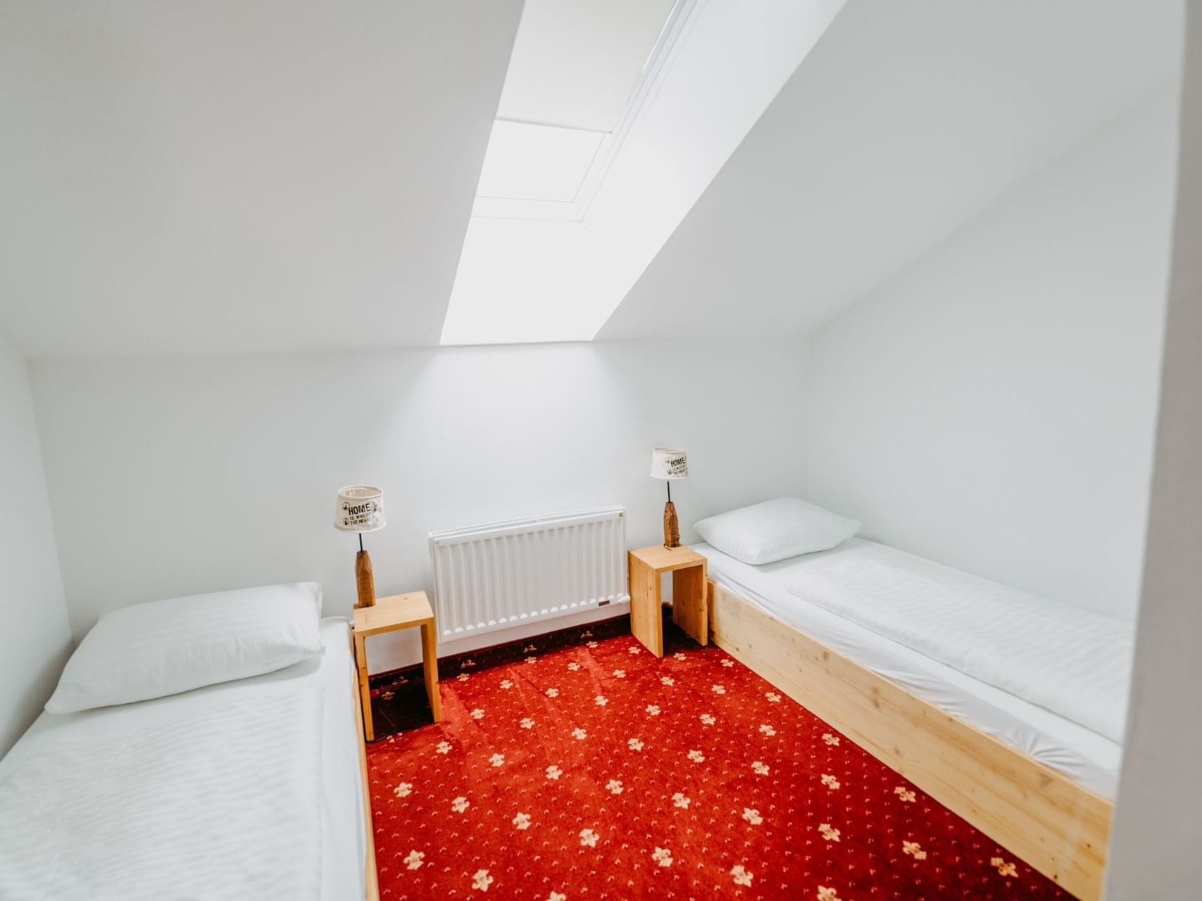 Zimmer mit rotem Teppich und Twinbetten.