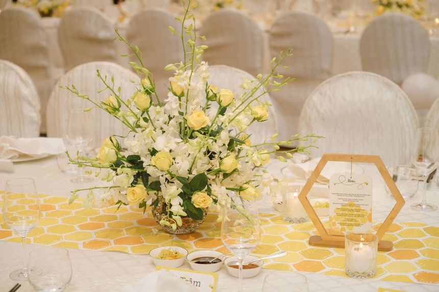 Floral centerpiece featuring yellow roses and orchids sits on a honeycomb-patterned table runner at Park Hyatt Saigon