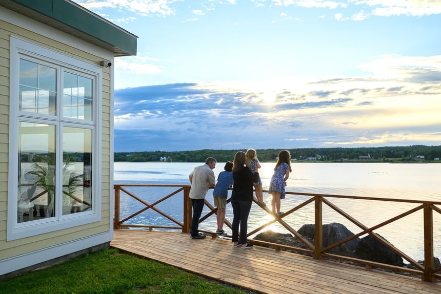 Family standing on a wooden deck by a tranquil lake at Rodd Miramichi River, best places to stay in Miramichi