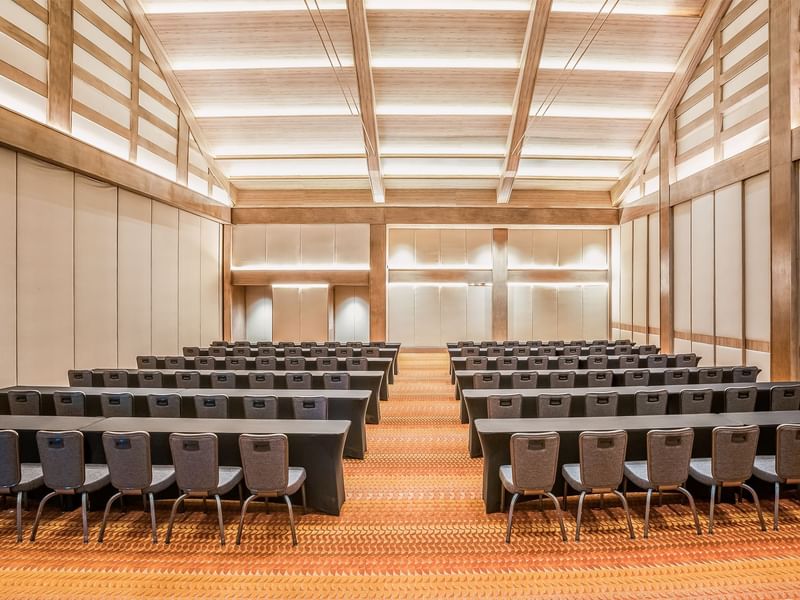 Brightly lit, spacious conference room with rows of black chairs and tables facing forward at Grand Fiesta Americana