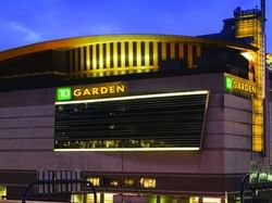 Illuminated TD Garden sports arena at night with surrounding city lights and a prominent bridge.