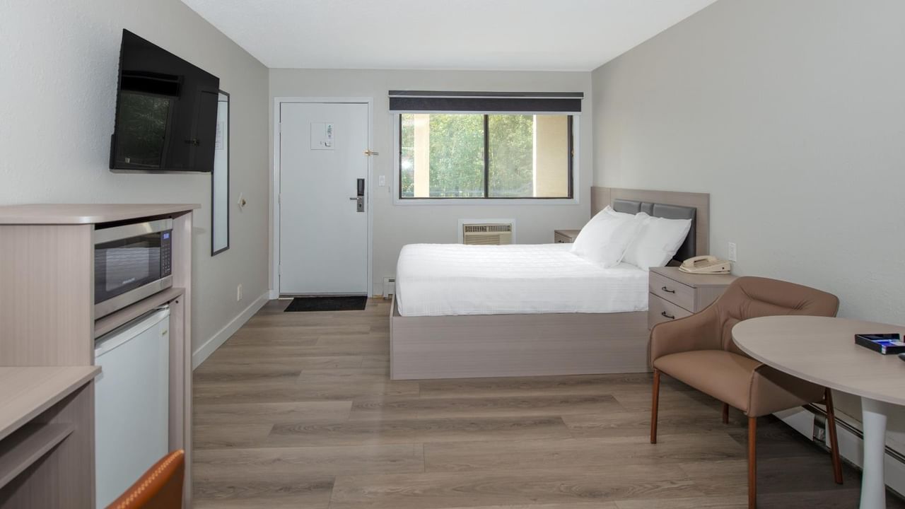 Spacious guest room at Coast Red Deer Hotel with queen bed, seating area and TV