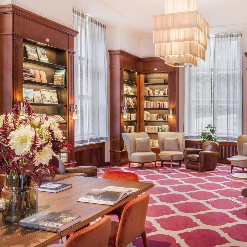 Library room with bookshelves, chairs & carped floors at Falkensteiner Spa Resort Mariánské Lázně