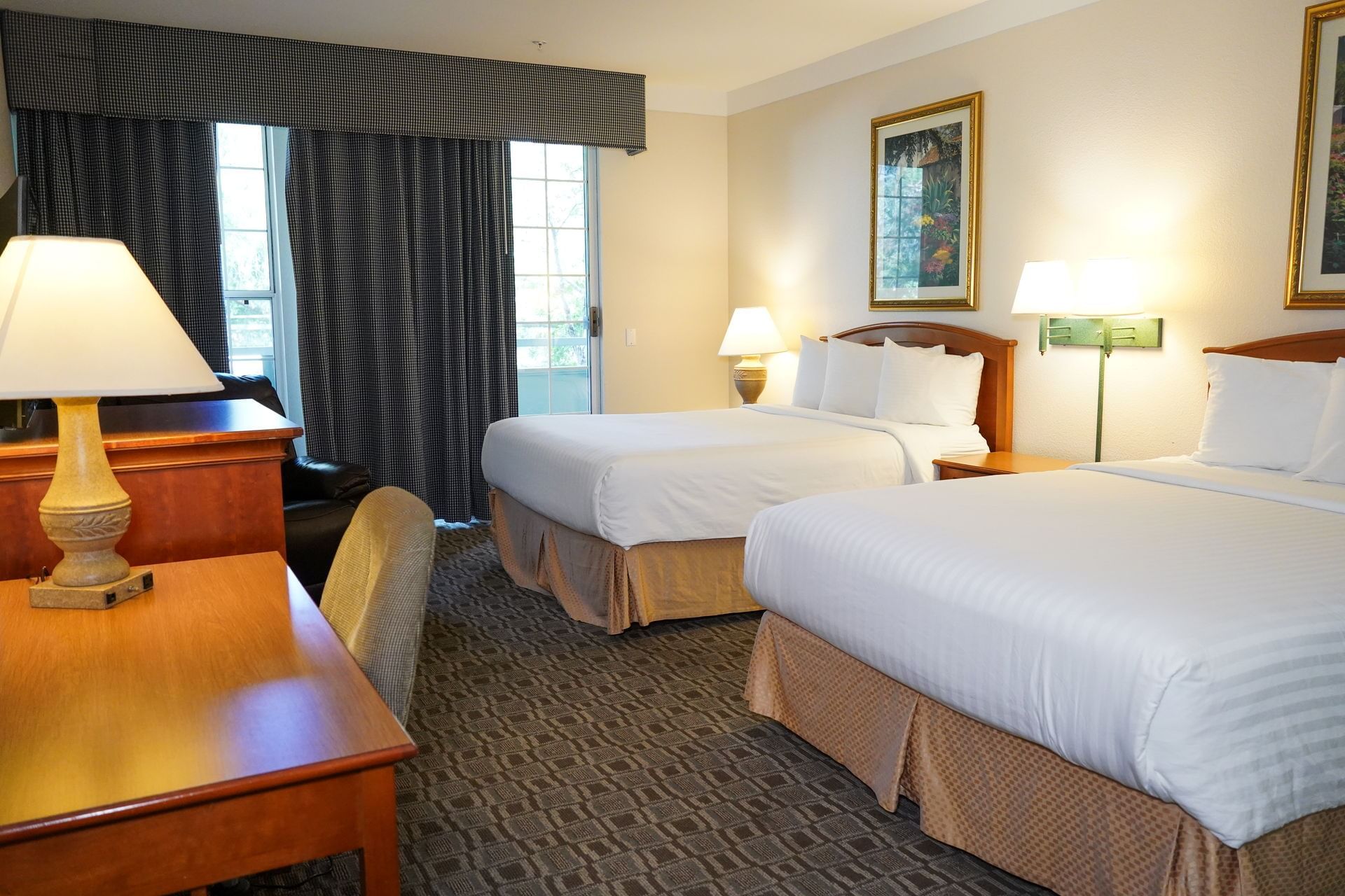 A standard hotel room with two queen beds, a desk, and a window.