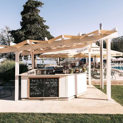 Outdoor pool bar with seating and umbrellas at Falkensteiner Premium Camping Zadar