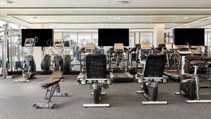 A modern gym with various equipment, including treadmills, stationary bikes, and weight machines.