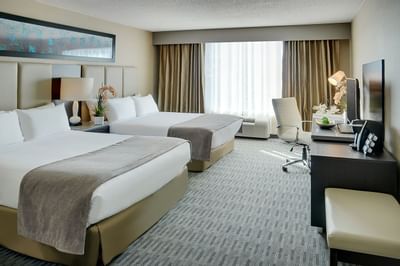 two beds in a hotel room facing a tv