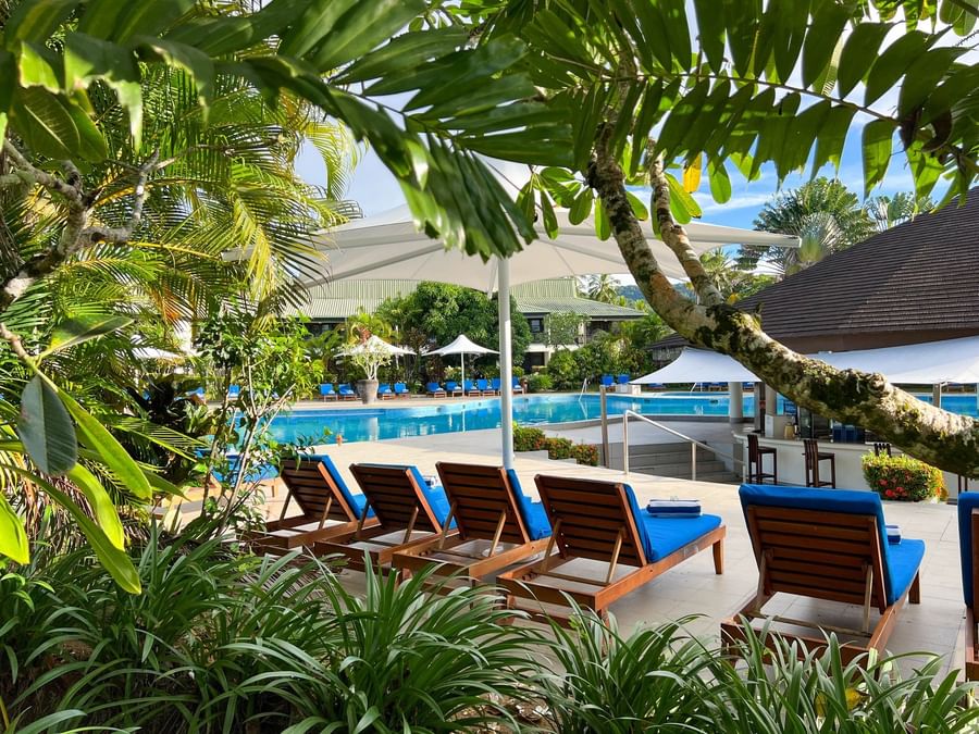 Lounge chairs by a pool and bar at The Naviti Resort Fiji.