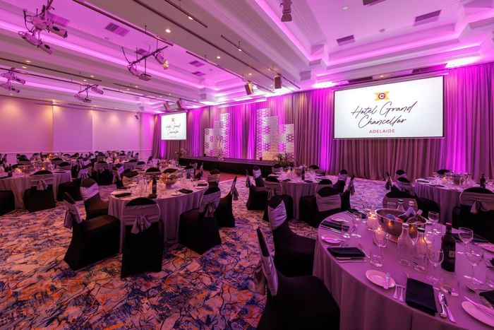 Banquet hall setup with purple lighting and white tablecloths at Hotel Grand Chancellor Adelaide