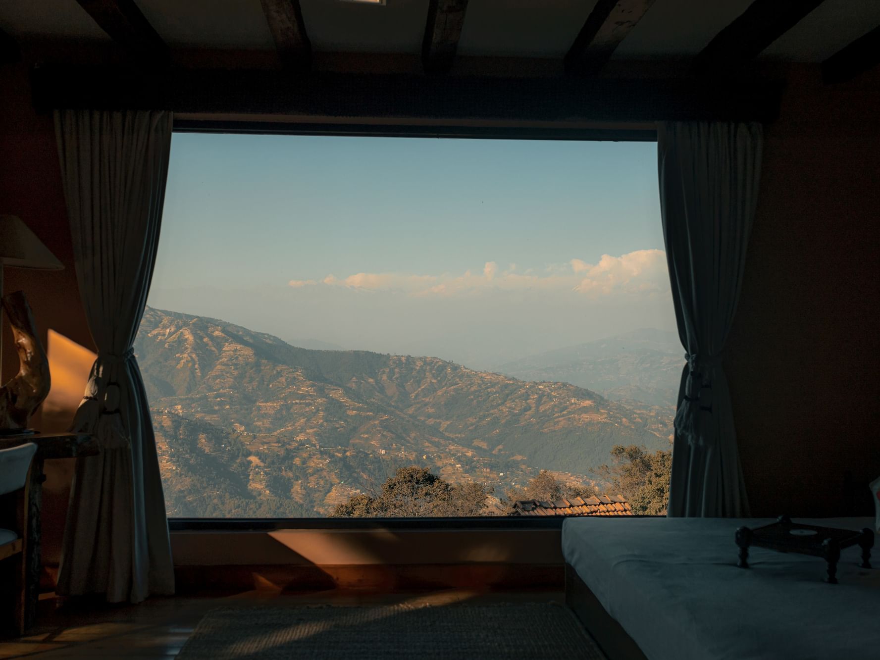 Royal Suite with a large window showcasing distant, rolling mountains at Dwarika's Himalayan Wellbeing
