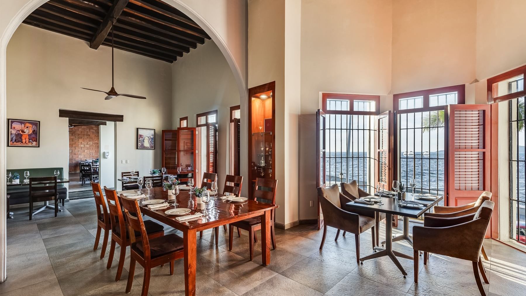 Restaurant dining area with an arched entryway and tables overlooking the ocean at Curamoria Collection