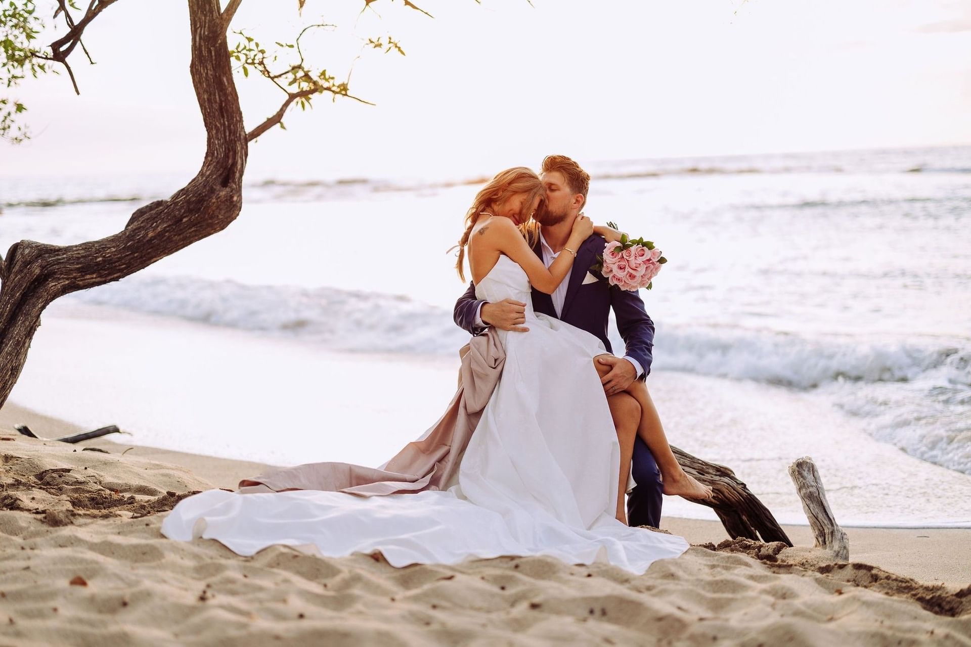 Romantic sunset embrace on the beach with the bride and groom near the ocean waves near Cala Luna Boutique Hotel