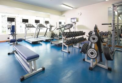 Gym interior with treadmills, elliptical machines, weight racks & blue flooring at Hotel Los Delfines & Casino