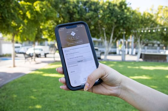 Mano sosteniendo un móvil con la aplicación del hotel para reservas y gestión de la cuenta de socio en Araiza Calafia